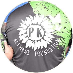 Three people wearing matching black and green shirts with a white logo and text on the back stand closely together. Description generated by AI